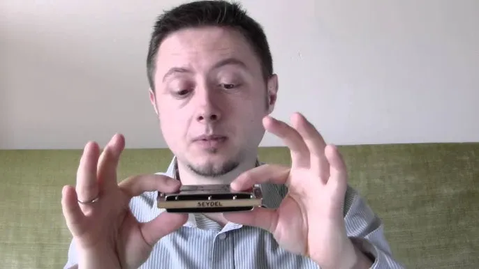 osoba trzymająca harmonijkę ustną, zbliżenie na dłonie