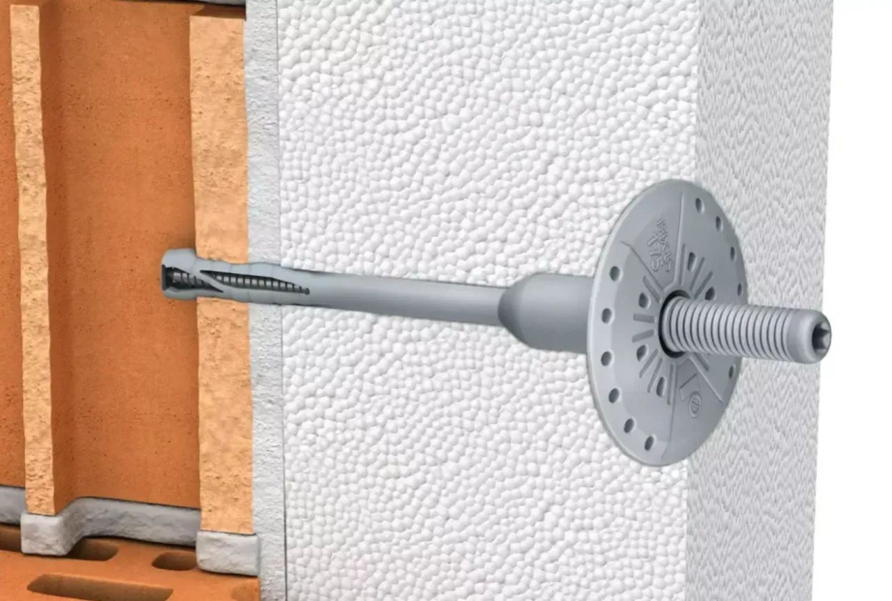 Przekrój ściany z widocznym kołkiem do styropianu, mocującym izolację do cegły.