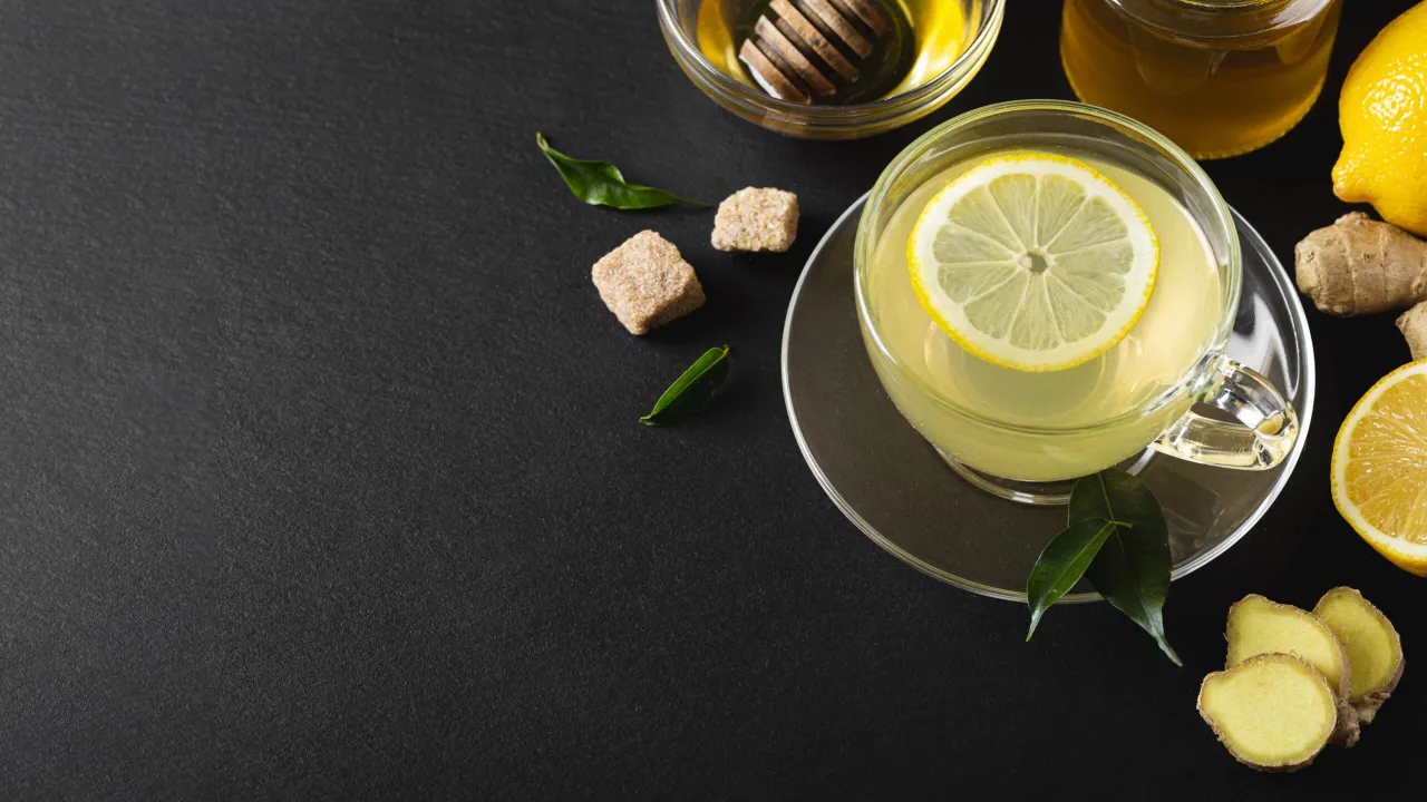 Herbata z cytryną i miodem, obok kawałki imbiru. Zastanawiasz się, ile imbiru do herbaty dodać dla najlepszego smaku?