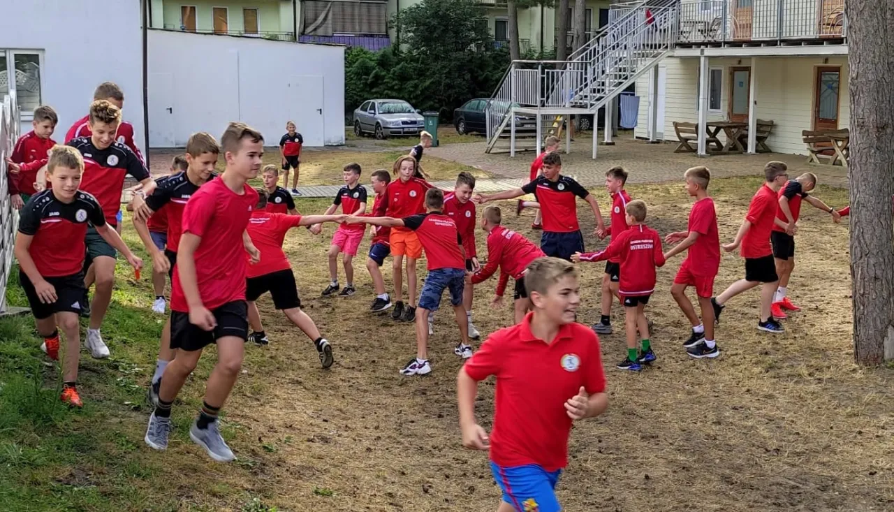 trener piłki nożnej tłumaczący ćwiczenie grupie dzieci