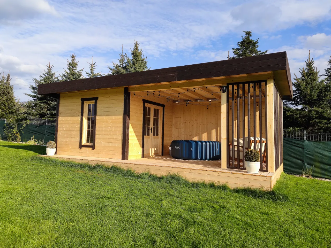 Drewniana altana z jacuzzi i wygodnymi miejscami do siedzenia. Solidne pokrycie dachu altany chroni przed słońcem i deszczem.