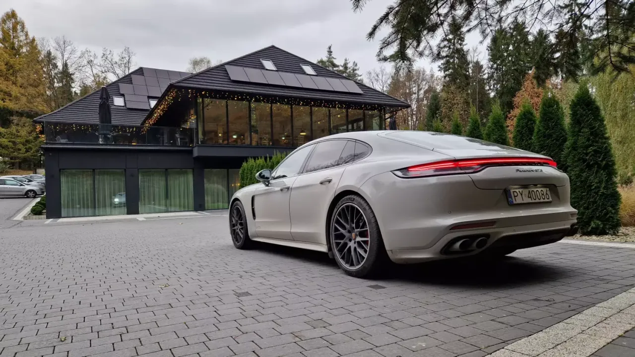 Elegancki Porsche Panamera, idealny zakup samochodu na firmę, parkuje przed nowoczesnym budynkiem z panelami słonecznymi.