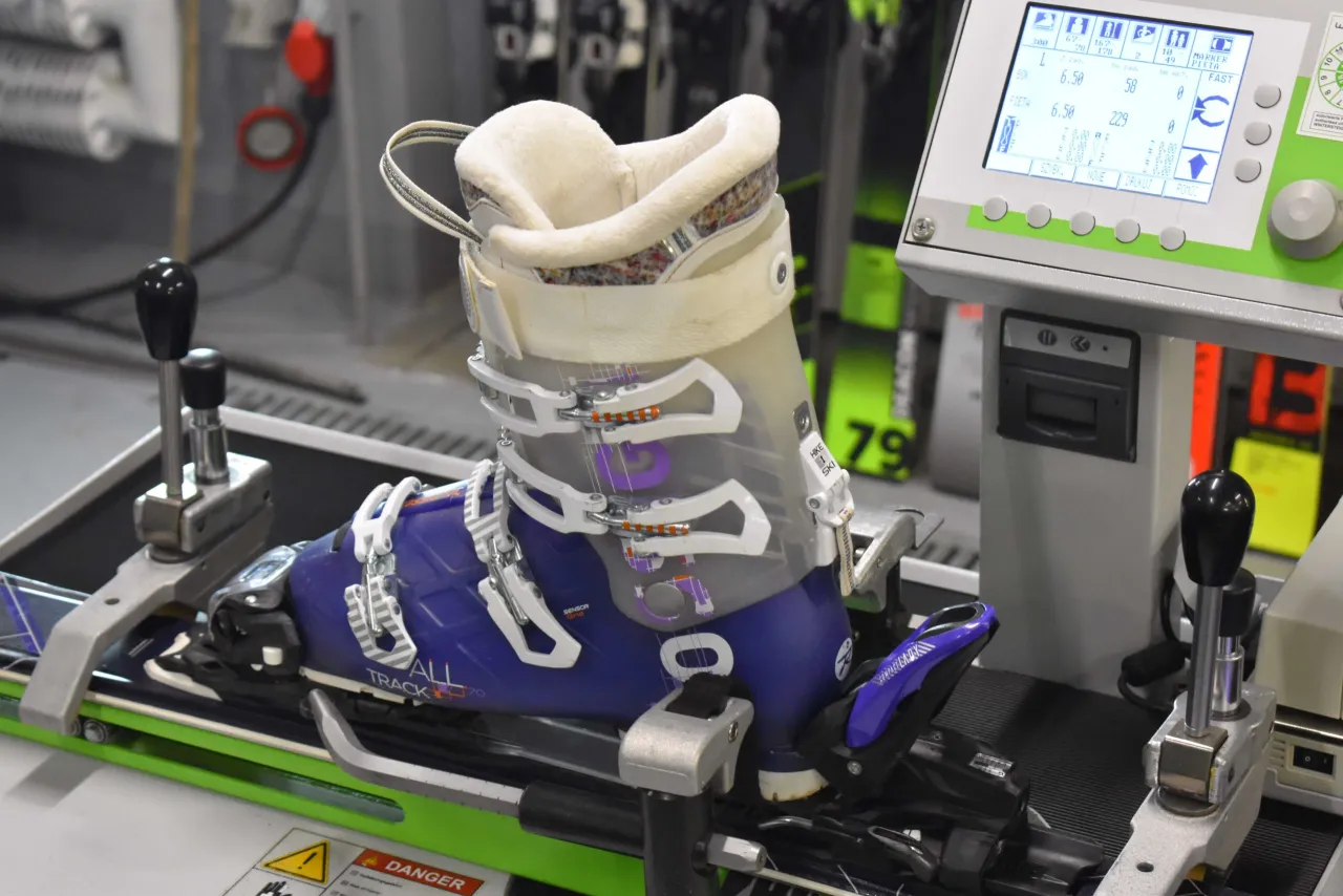 Narty z butem na maszynie do ustawiania wiązań. Ekran pokazuje parametry, jak ustawić DIN w nartach.