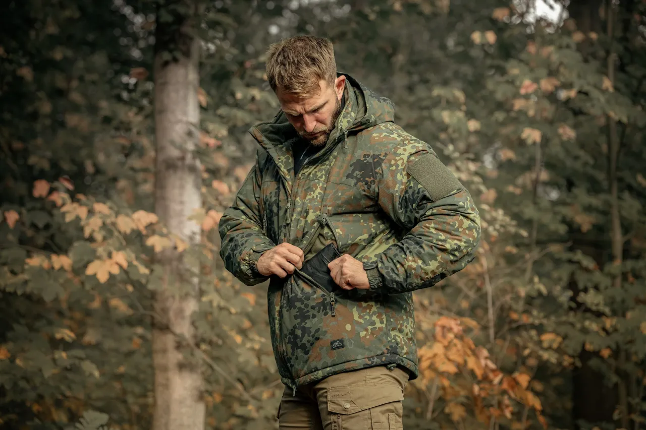 Mężczyzna w kurtce moro, idealnej do lasu, sprawdza zawartość kieszeni. To, co zakłada myśliwy, musi być praktyczne i maskujące.