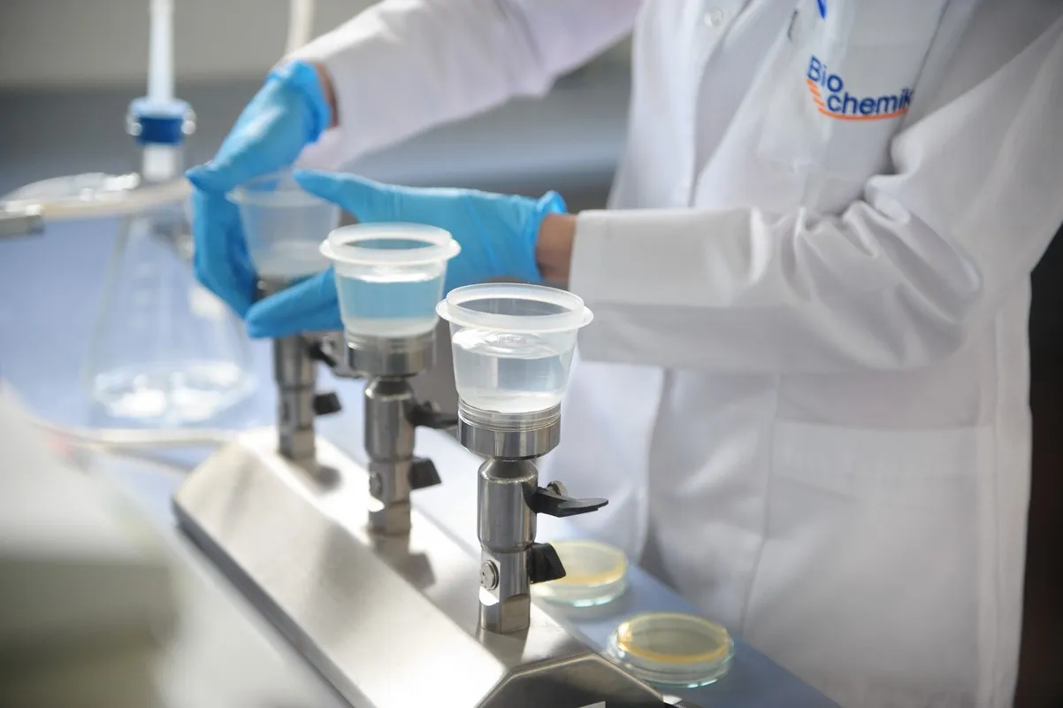 Pracownik w białej kurtce laboratoryjnej z logo 