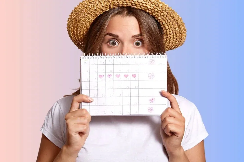 Kobieta z bólem brzucha i kalendarzem cyklu menstruacyjnego