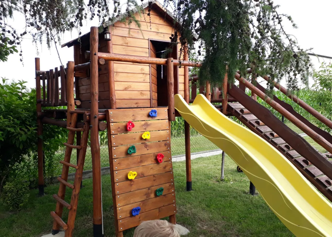 Drewniany domek dla dzieci projekt: z drabinką, zjeżdżalnią i ścianką wspinaczkową. Idealne miejsce do zabawy na świeżym powietrzu.