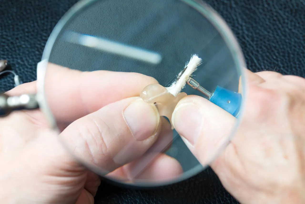 Precyzyjna praca przy aparacie słuchowym. Zastanawiasz się, ile kosztuje dobry aparat słuchowy?