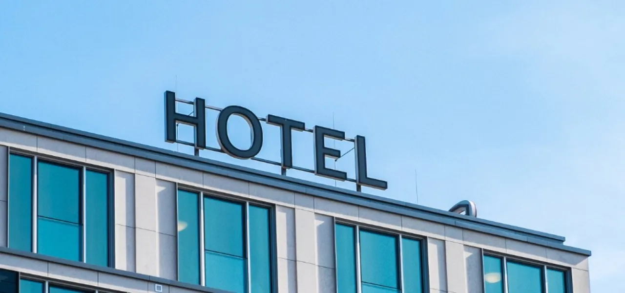 Duży napis HOTEL na dachu nowoczesnego budynku z niebieskimi oknami. To miejsce, gdzie można odpocząć, czyli co to znaczy resort.