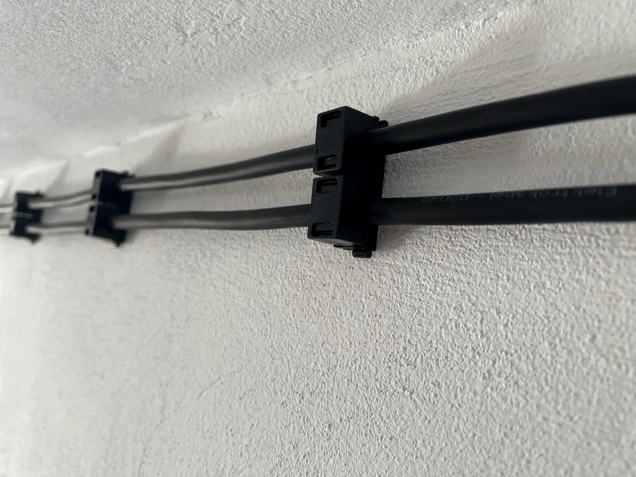 Czarne klipsy do mocowania przewod&oacute;w elektrycznych do drewna, zapewniające schludny wygląd instalacji.