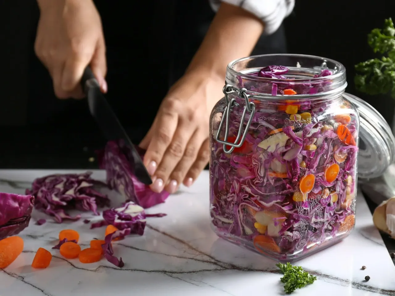 Przygotowanie kiszonki na zimę: siekanie czerwonej kapusty z marchewką do słoika.