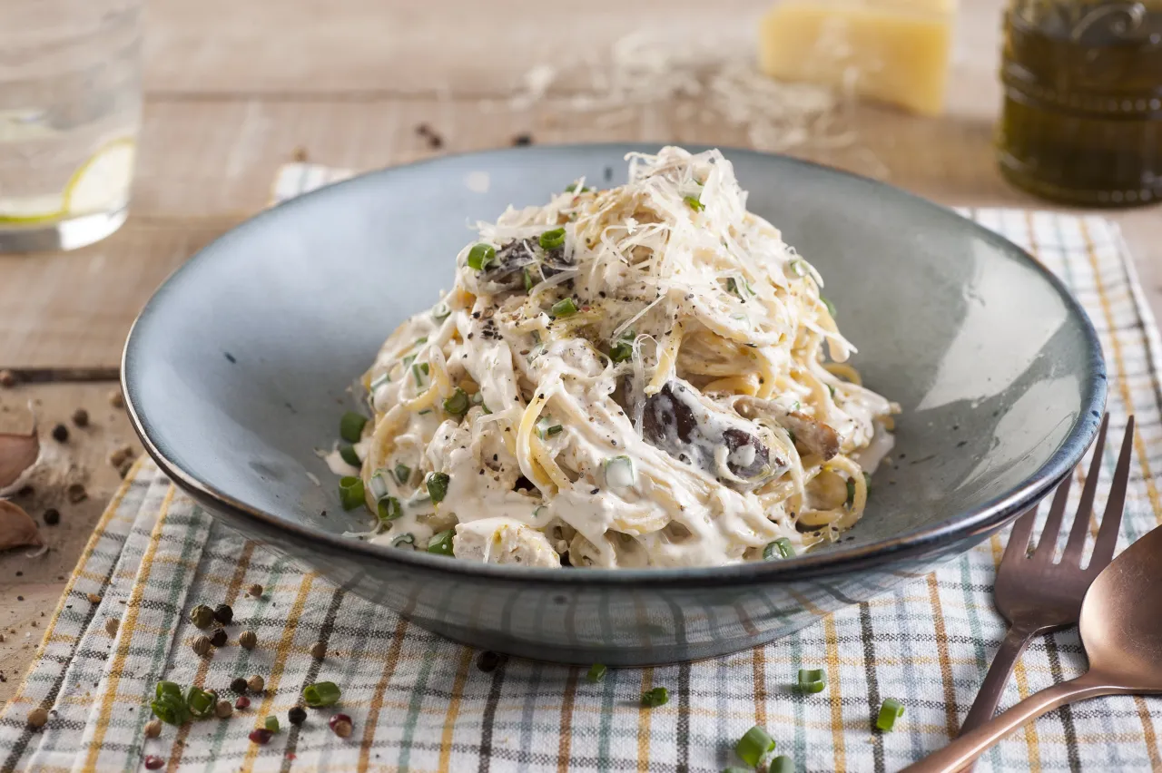 plato de pasta cremosa con pollo y champi&ntilde;ones en un restaurante