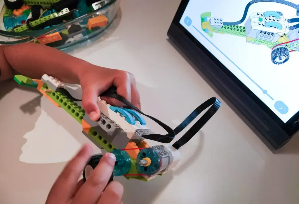 instruktor pomaga dziecku programować robota z Lego na tablecie