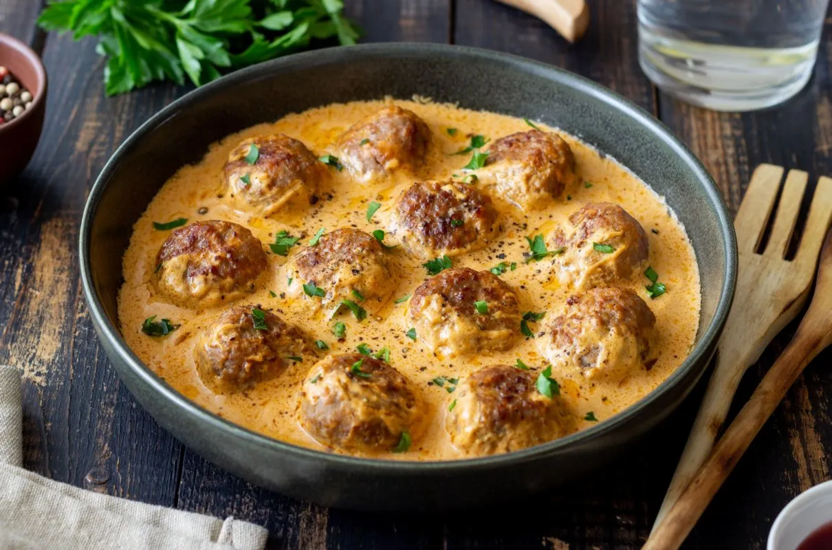 Pyszne klopsiki z mielonego w kremowym sosie, idealne co z mielonego na obiad. Posypane natką pietruszki.