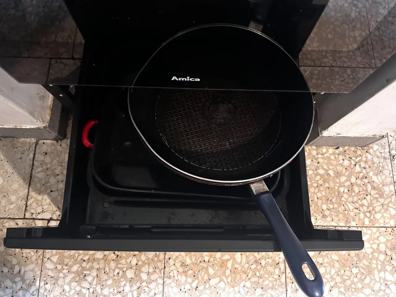 Stara, porysowana patelnia Amica leży na płycie indukcyjnej. Zastanawiasz się, gdzie wyrzucić starą patelnię?