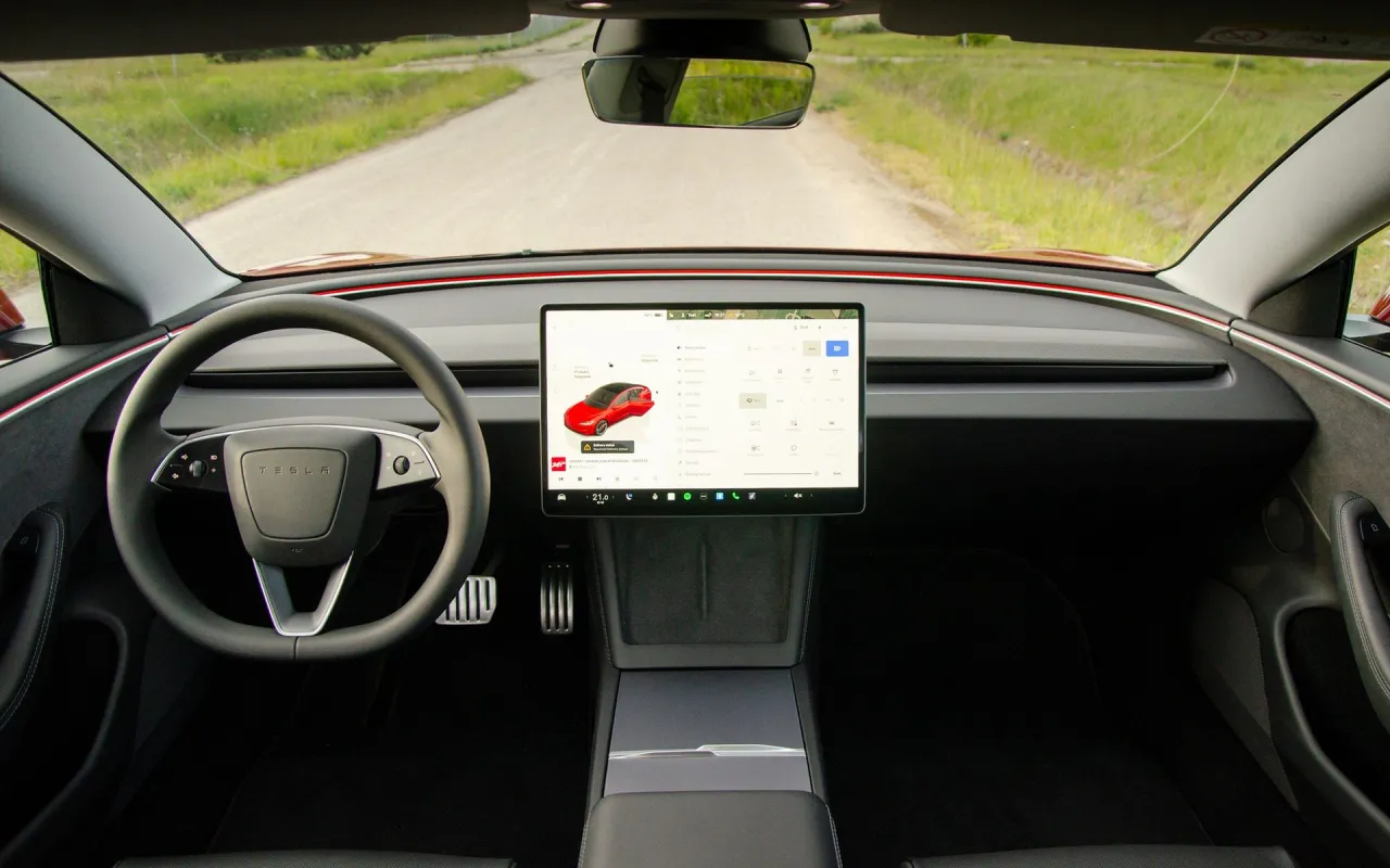 Wnętrze Tesli Model 3. Na ekranie widok samochodu, a obok opcje. Zastanawiasz się, tesla model 3 ile koni?