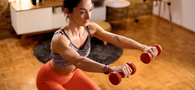 Osoba wykonująca ćwiczenia siłowe z hantlami