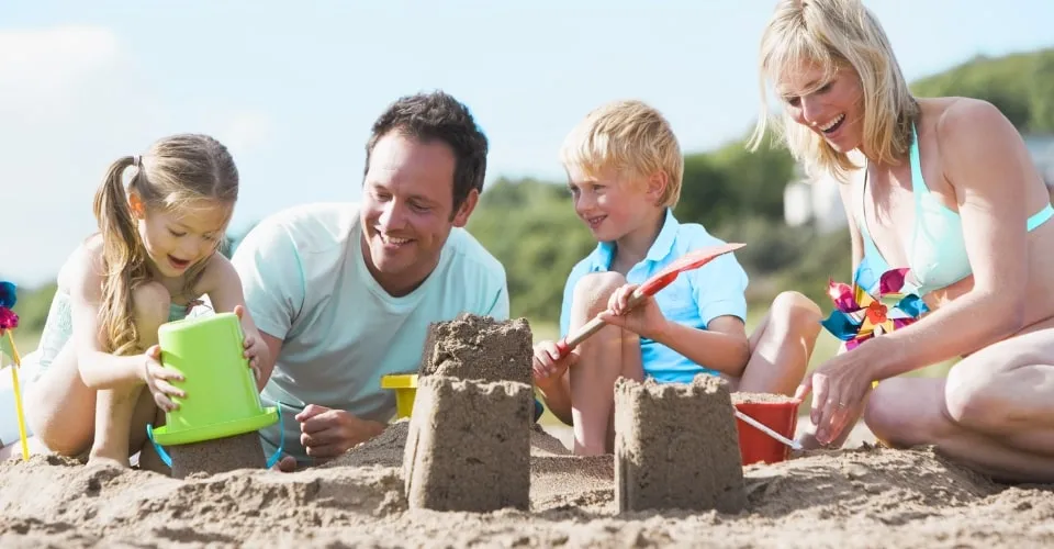 Rodzina z dzieckiem na plaży budująca zamek z piasku