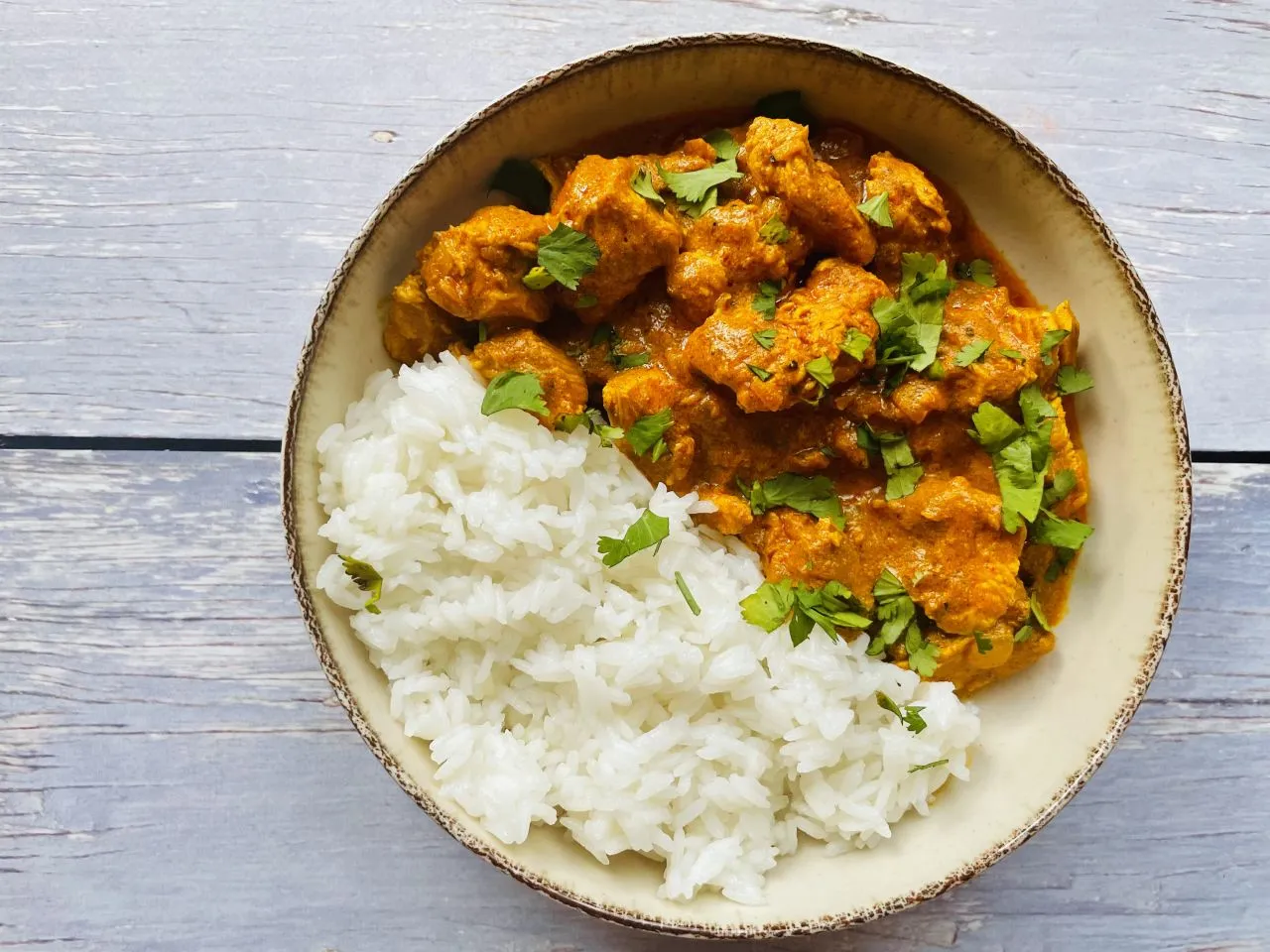 Kurczak curry w misce z ryżem i kolendrą