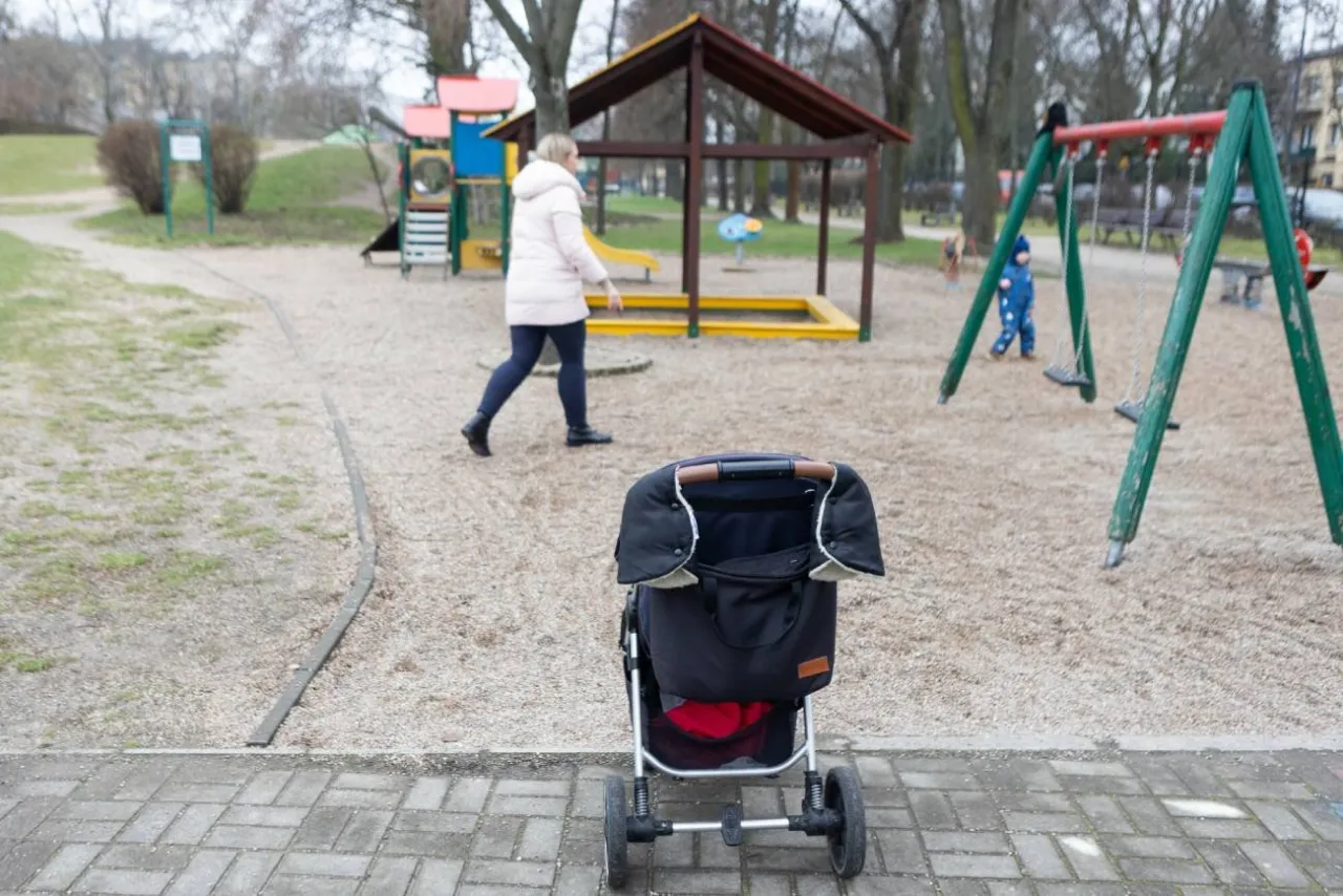 Rodzice z dzieckiem przygotowujący się do wyjścia na plac zabaw, sprawdzający pogodę