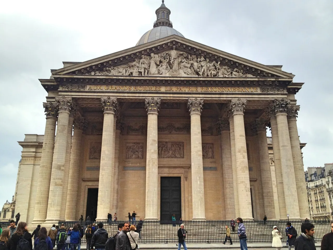 Majestatyczny Panteon w dzielnicy łacińskiej Paryża, z kolumnami i rzeźbami. Tłum turystów podziwia architekturę.