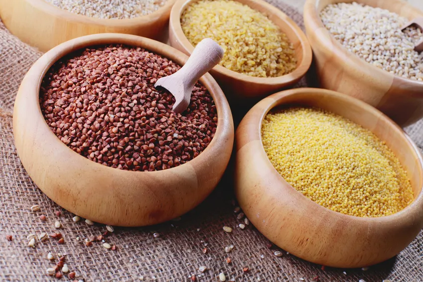 różne rodzaje kasz w miseczkach na drewnianym stole