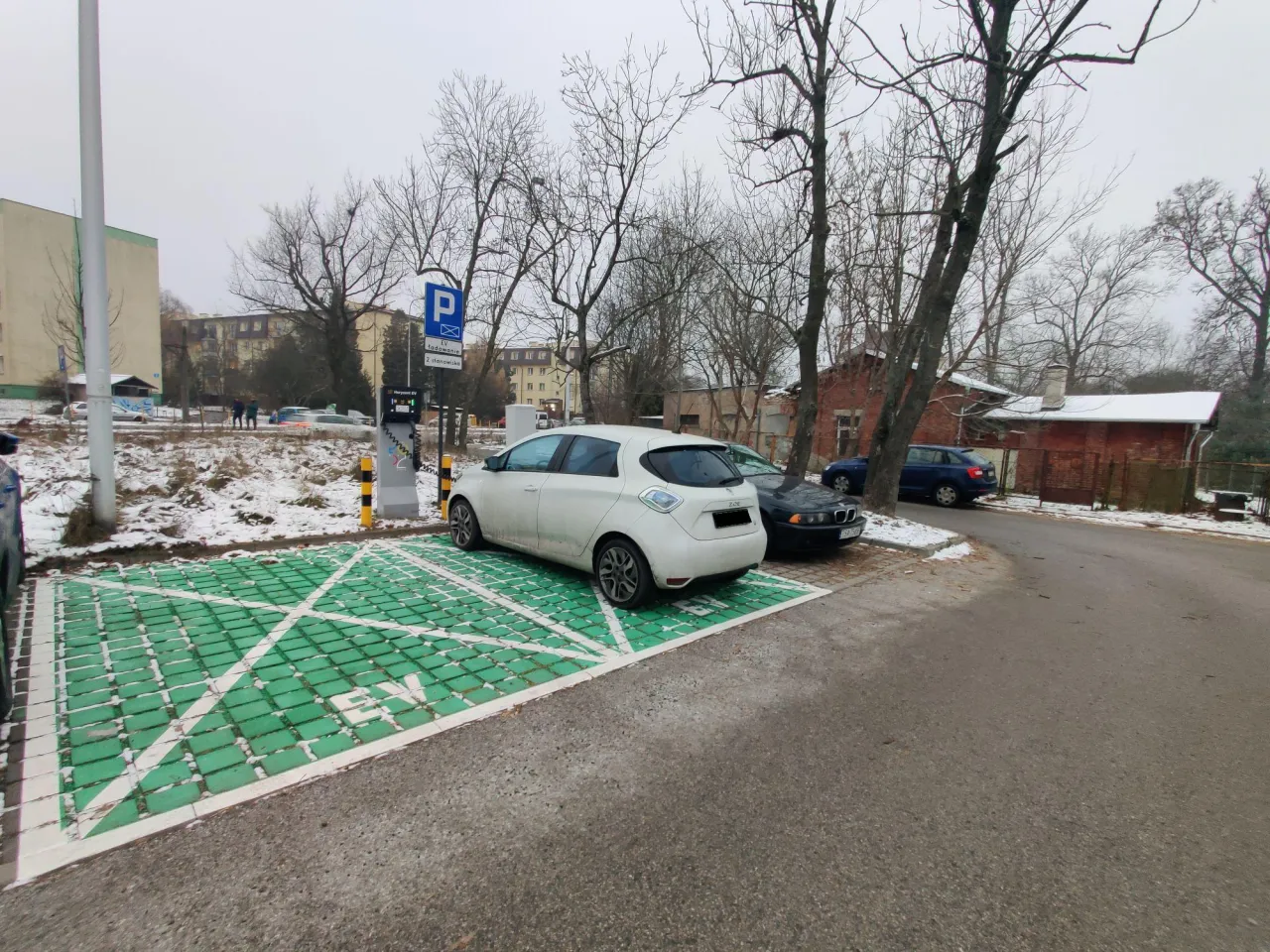 Stacja ładowania pojazdów elektrycznych w pobliżu PKP Łódź Widzew. Dwa samochody elektryczne czekają na naładowanie.