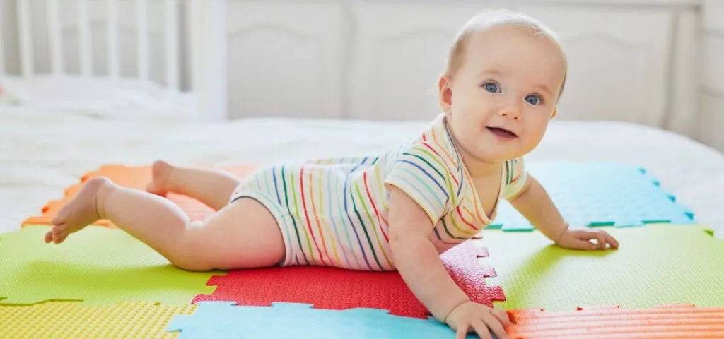 niemowlę leżące na brzuchu podnoszące główkę