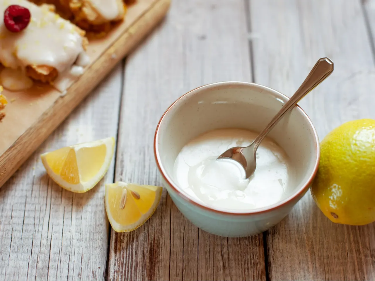 Jak zrobić dobry lukier do sernika? Składniki: miseczka z lukrem, cytryna, kawałki sernika.