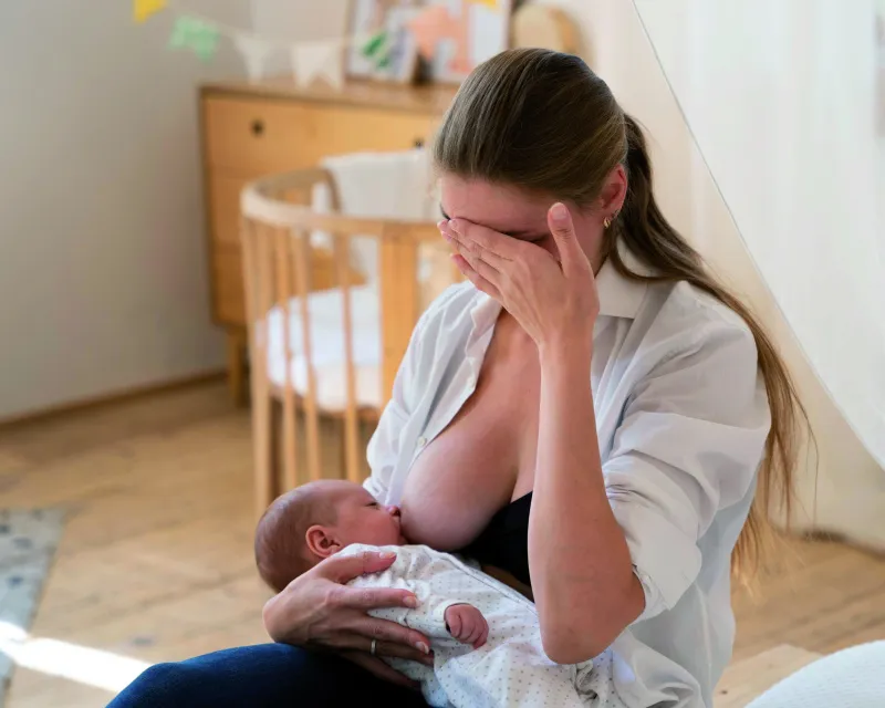 Kobieta zrelaksowana, trzymająca dziecko, symbolizująca koniec karmienia piersią