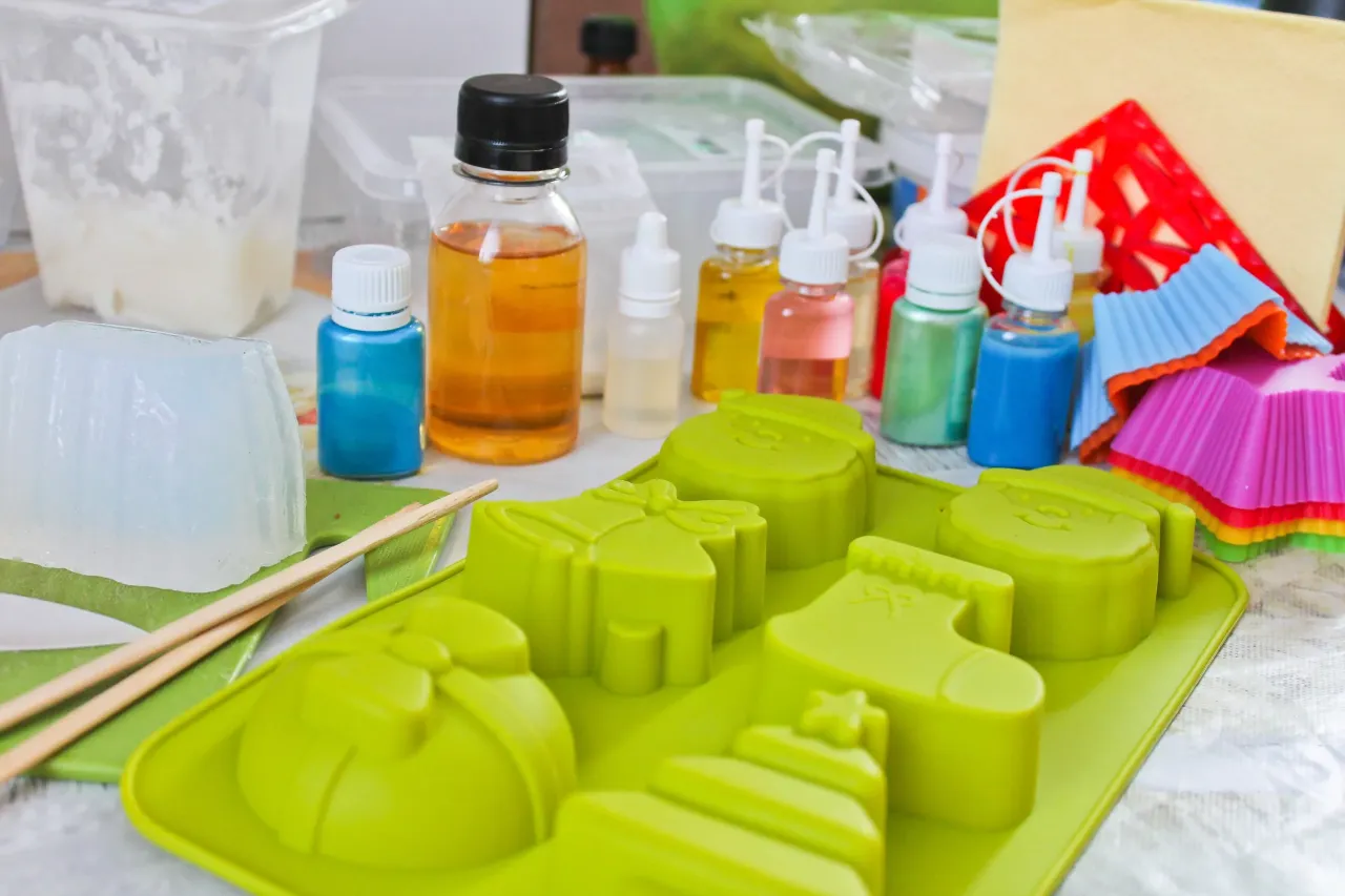 Materiały do zrobienia mydła glicerynowego: baza, barwniki, foremki w kształcie świątecznym.