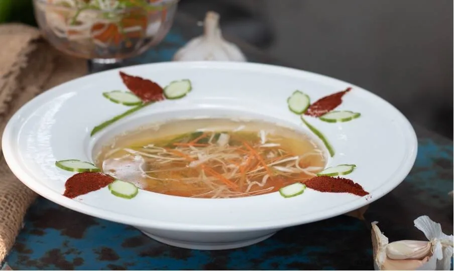 klare consomm&eacute; mit einlagen serviert