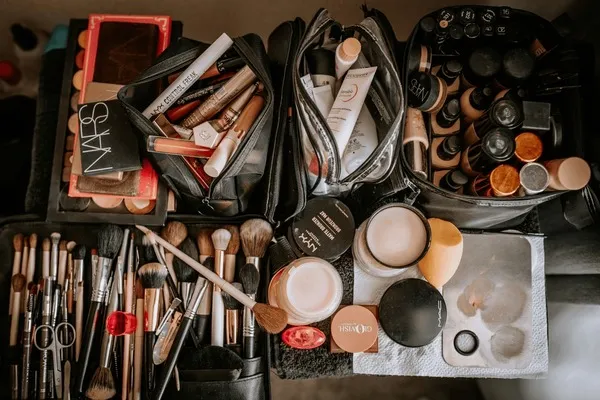 Flatlay mit verschiedenen Kosmetikprodukten wie Lippenstift, Puder und Mascara