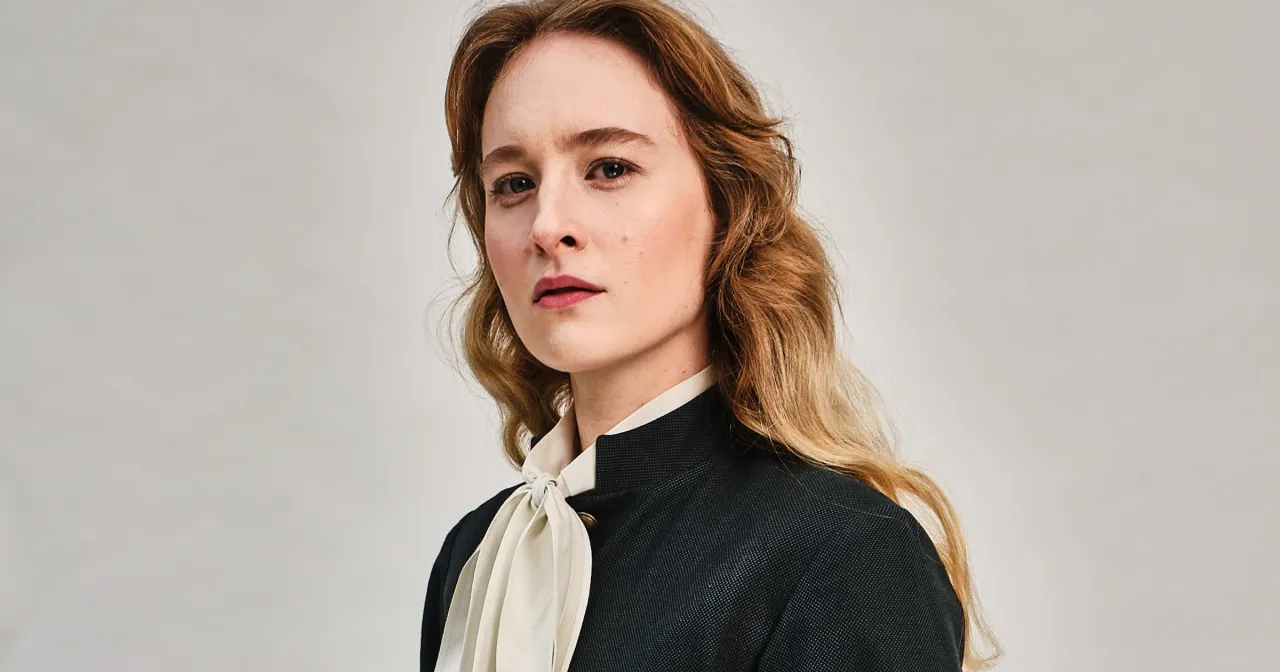 Portret Marii Kowalskiej, aktorki o rudych włosach, w eleganckim żakiecie i kremowej bluzce z kokardą.