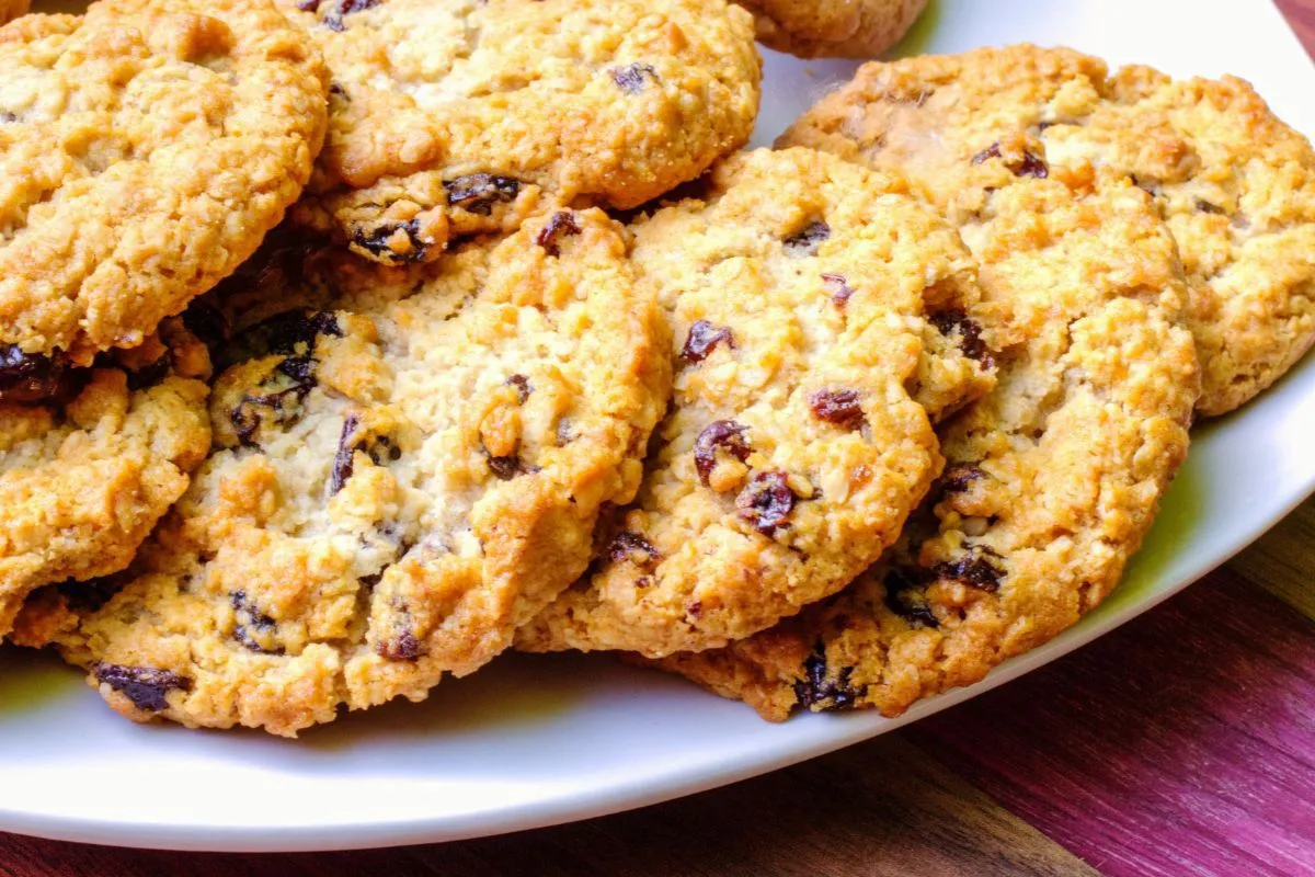 Stos chrupiących ciasteczek owsianych z rodzynkami na białym talerzu. Idealne na przekąskę.