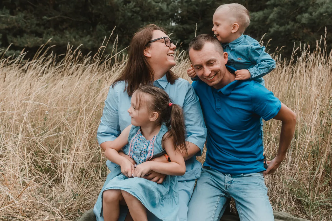 Szczęśliwa rodzina w polu, idealna na imprezy, na które wynajmujemy fotografa. Radosne chwile uchwycone przez obiektyw.