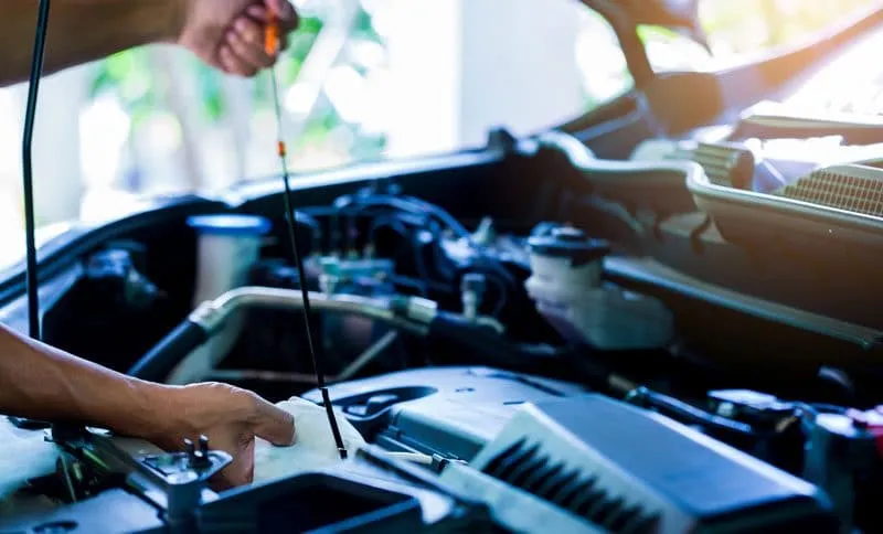 personne inspectant une pièce de moteur de voiture d'occasion