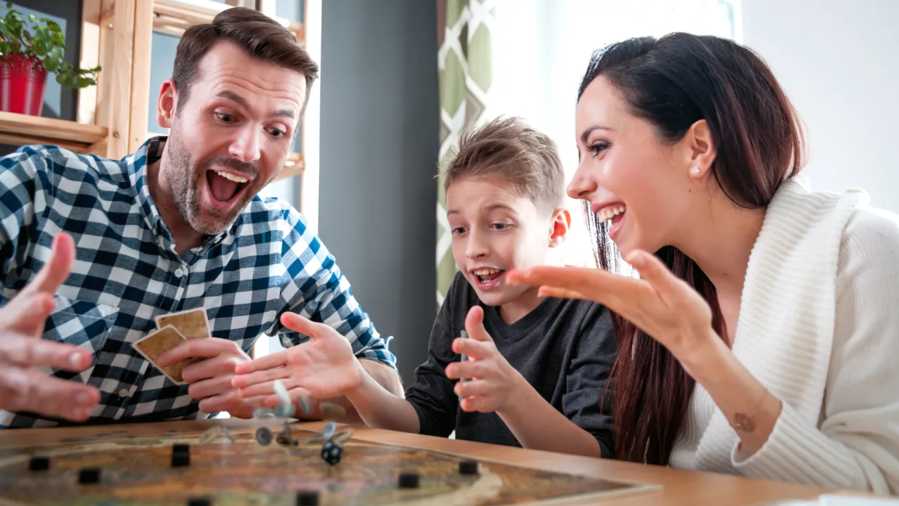 rodzina grająca w plansz&oacute;wki z uśmiechem