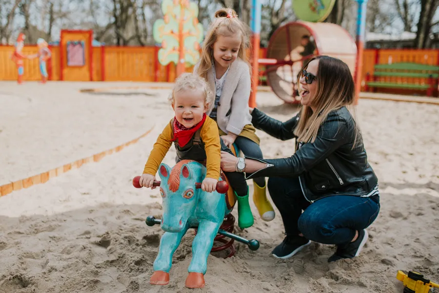 roczne dziecko bawi się na placu zabaw z rodzicem