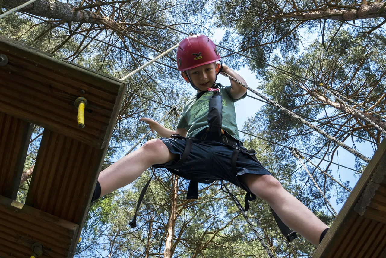 dziecko w uprzęży w parku linowym