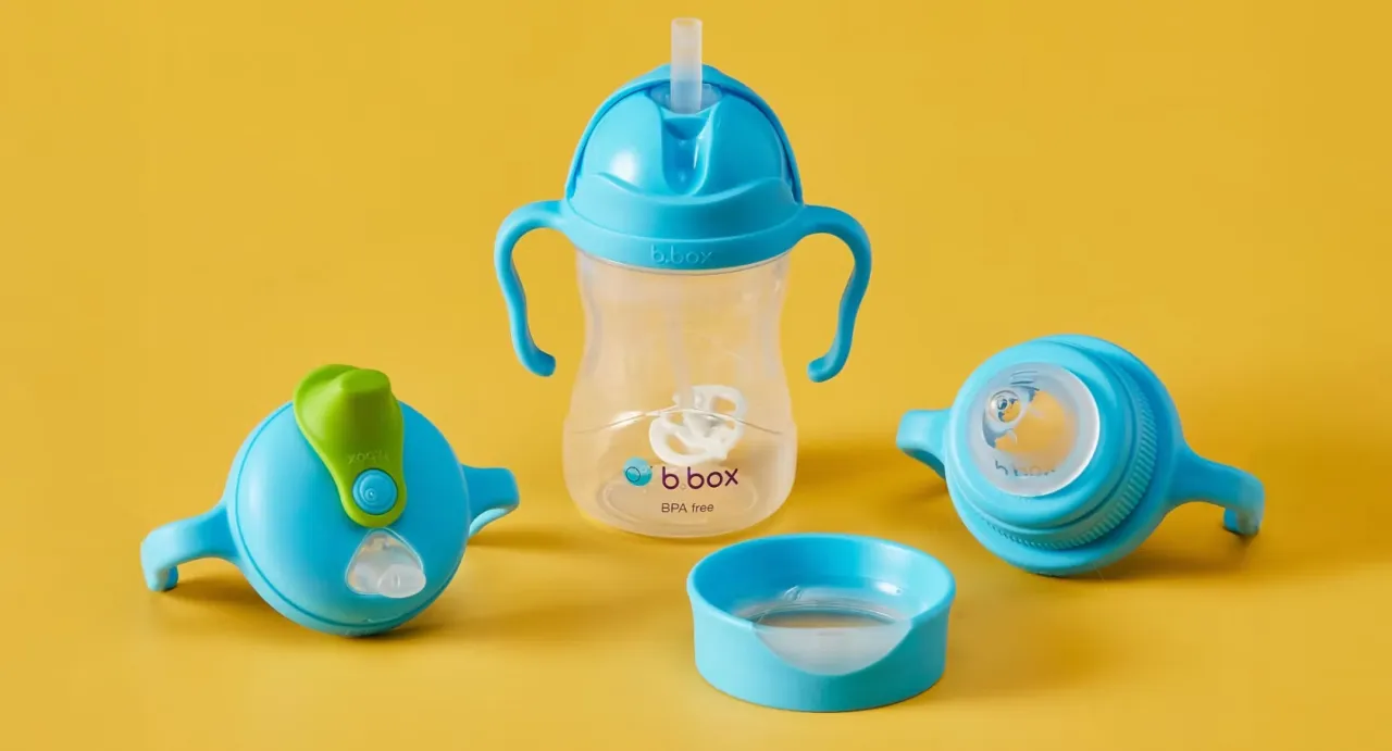 Dziecko pije z kubka otwartego, uśmiechnięte