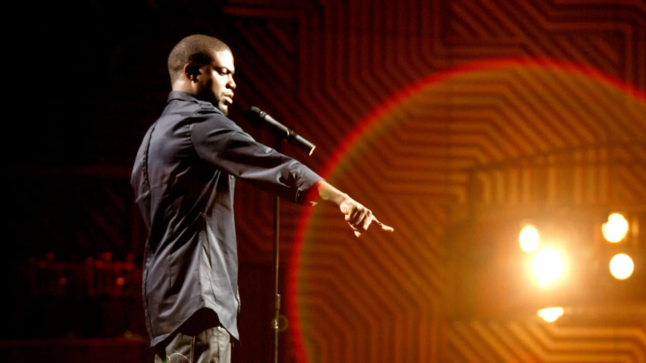 Kevin Hart stand up na scenie, wskazując palcem w stronę publiczności.