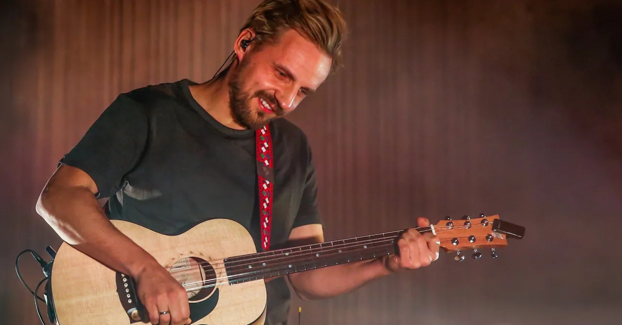 Uśmiechnięty muzyk gra na gitarze. Zastanawiasz się, ile trwa koncert Domagały?