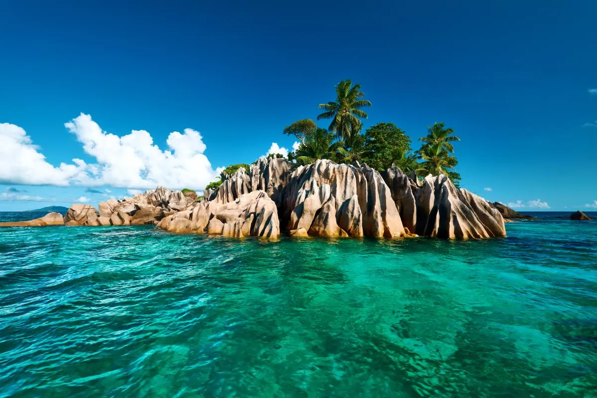 Rajska wyspa z palmami i skałami, turkusowa woda. Czy na Seszelach jest bezpiecznie? Tak, to raj na ziemi.