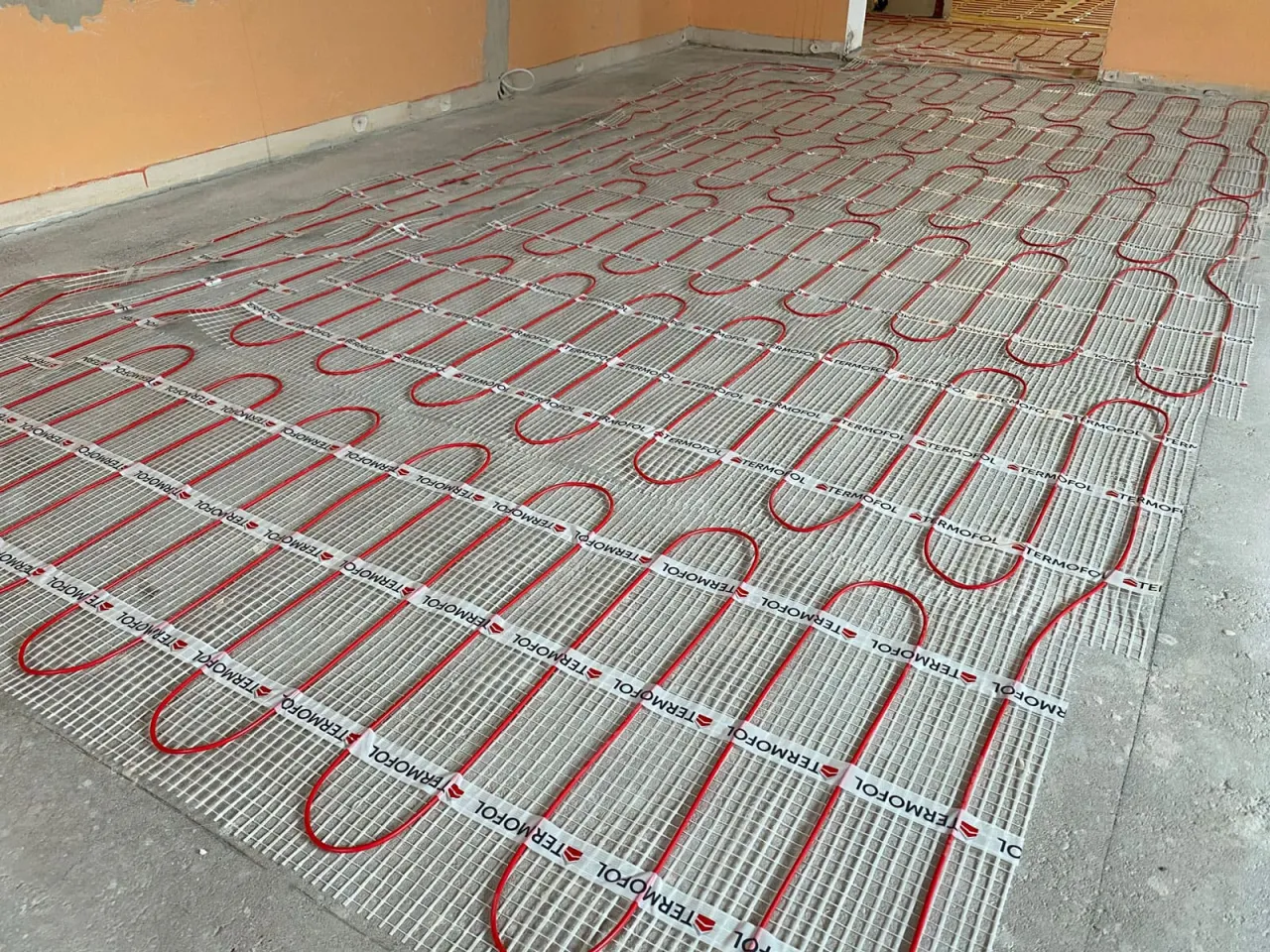 Przed wylewkami podłogowymi, na siatce ułożono czerwone rurki ogrzewania podłogowego.