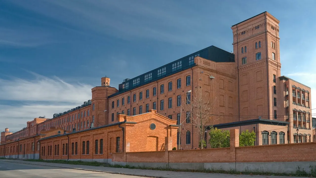Imponujący kompleks ceglanych budynk&oacute;w z wieżą, idealny punkt na mapie, co zwiedzić w Łodzi.