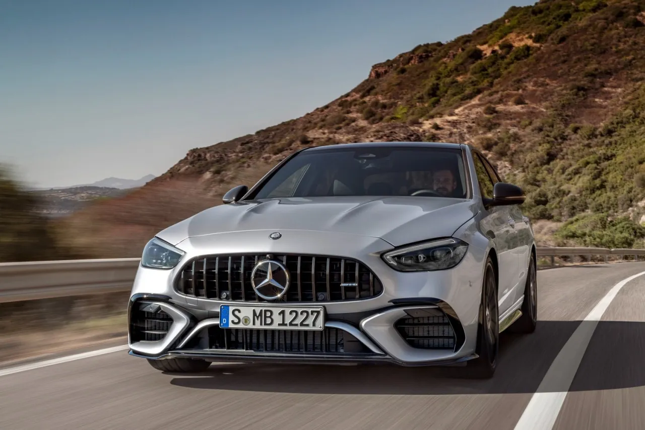 Srebrny Mercedes-AMG C63 Coupe pędzi po krętej drodze, ukazując swoją sportową sylwetkę na tle górskiego krajobrazu.