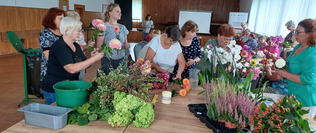 Kobiety tworzą kompozycje kwiatowe, ucząc się jak założyć klub seniora.