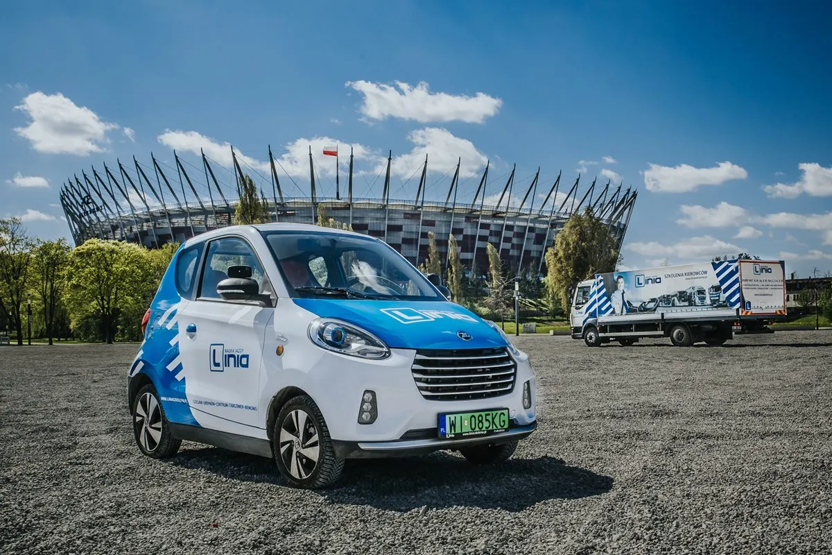 Mały samoch&oacute;d elektryczny i ciężar&oacute;wka szkoleniowa przed stadionem. Prawo jazdy kat B1 czym można jeździć? Takimi pojazdami!