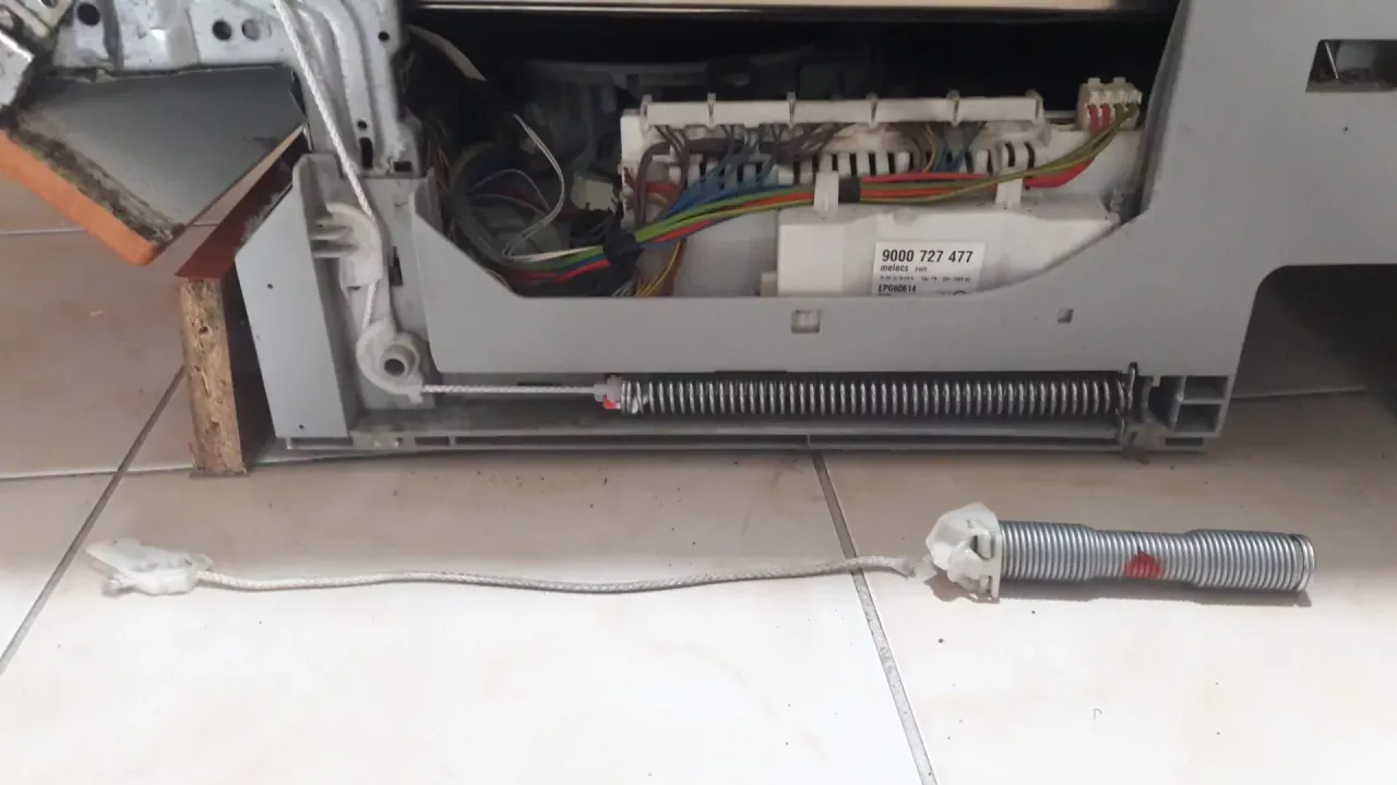 Naprawa zmywarki Whirlpool: jak zamontować front. Widoczne sprężyny i linki mocujące drzwi.